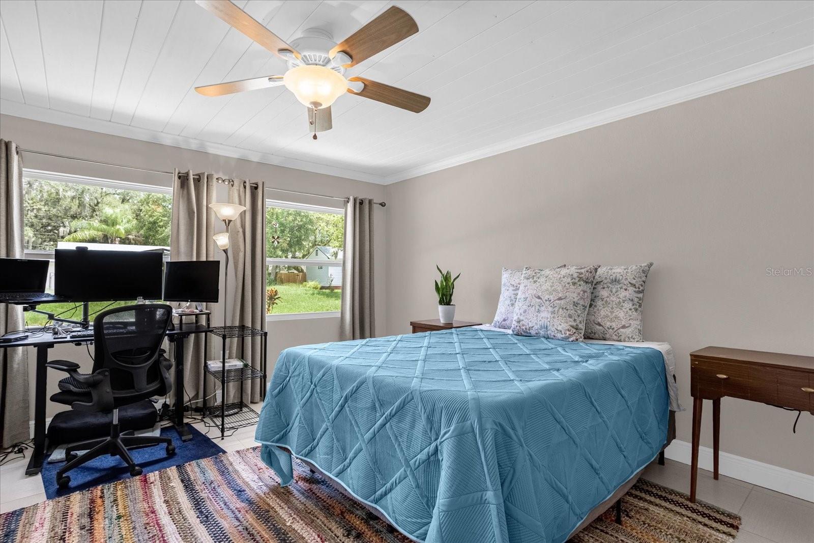 Bedroom overlooking the front yard. All tile with linear wood plank ceiling, crown molding, and plenty of beautiful natural sunlight.