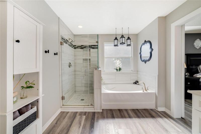 Your private bath has been updated with new vanities, hardware, decorative mirrors and lighting, there is plenty of storage, a soaking tub and separate tiled shower behind seamless glass doors!