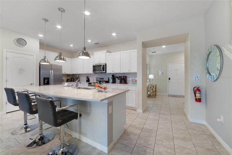 The bright open concept centers around a spacious kitchen featuring a large island complete with breakfast bar seating under pendant lighting, plenty of storage in the cabinets and closet pantry, custom backsplash and stainless steel appliances!