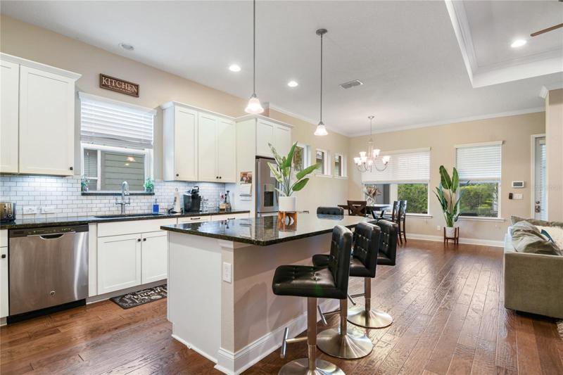 The spacious kitchen offers the home chef the ability to stay involved while entertaining family and friends surrounded by modern shaker style 42” cabinetry, stainless steel appliances, stone counters, subway tile backsplash, closet pantry and large island with breakfast bar seating under pendant lighting!