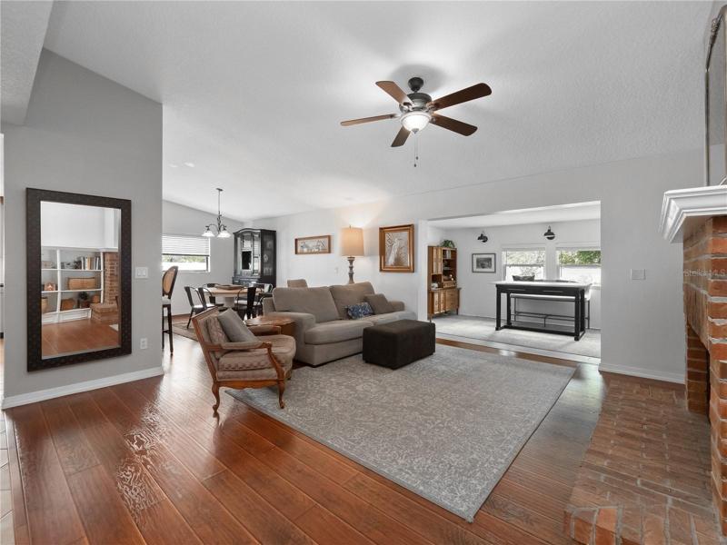 The large living room features dramatic vaulted ceilings, wood floor, wood burning fireplace and built in shelving.