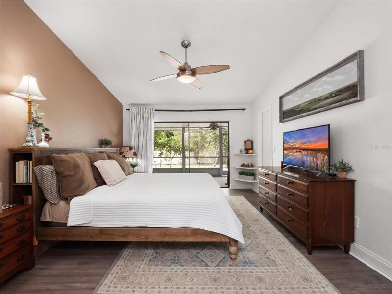 The primary suite has updated flooring, a walk in closet, access to the covered, screened in lanai and large backyard. The primary en-suite bathroom has been updated with solid wood dual sink vanity topped with granite along with a walk in shower.