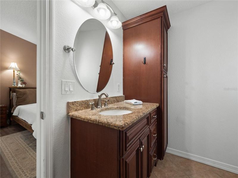 The primary suite has updated flooring, a walk in closet, access to the covered, screened in lanai and large backyard. The primary en-suite bathroom has been updated with solid wood dual sink vanity topped with granite along with a walk in shower.