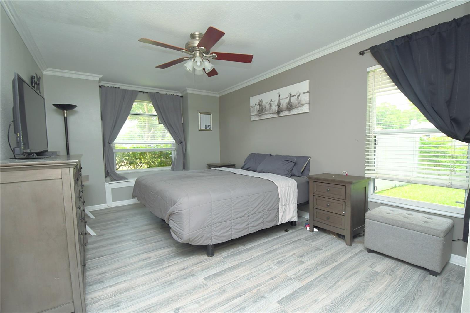 The master suite offers serenity and luxury with an ensuite bath, a large walk-in closet, a ceiling fan, crown molding, and a charming window seat with storage.