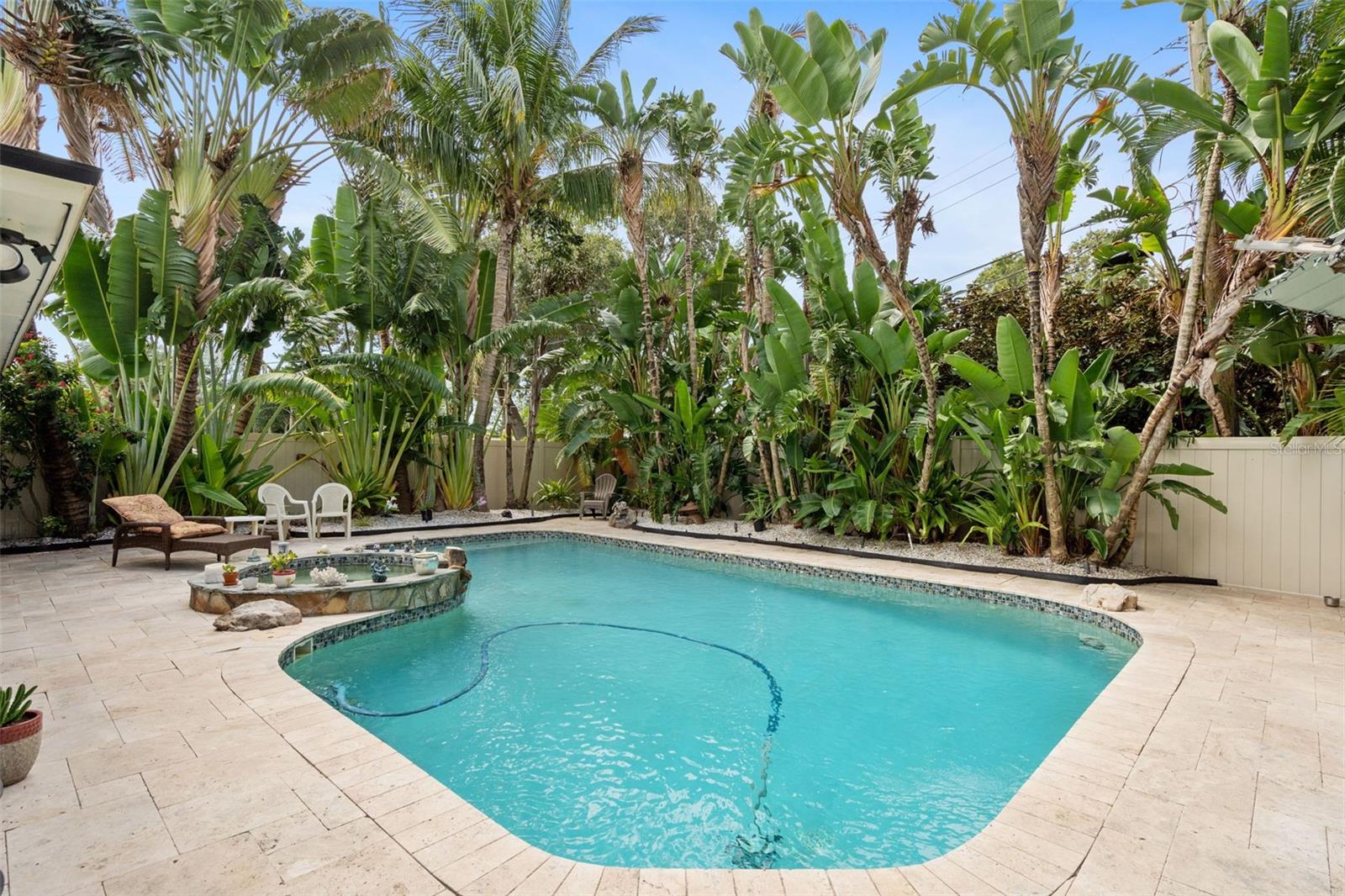 A saltwater pool and spa are surrounded by brick pavers