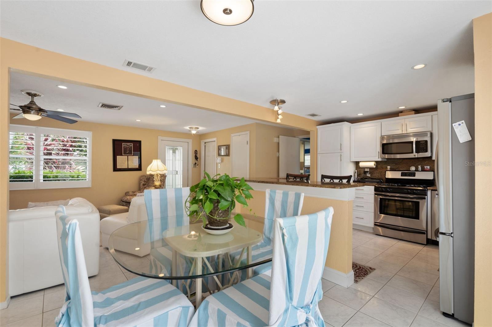 Kitchen, living and dining - open concept plans. Notice the plantation shutters and lovely landscaping looking out the living room window.