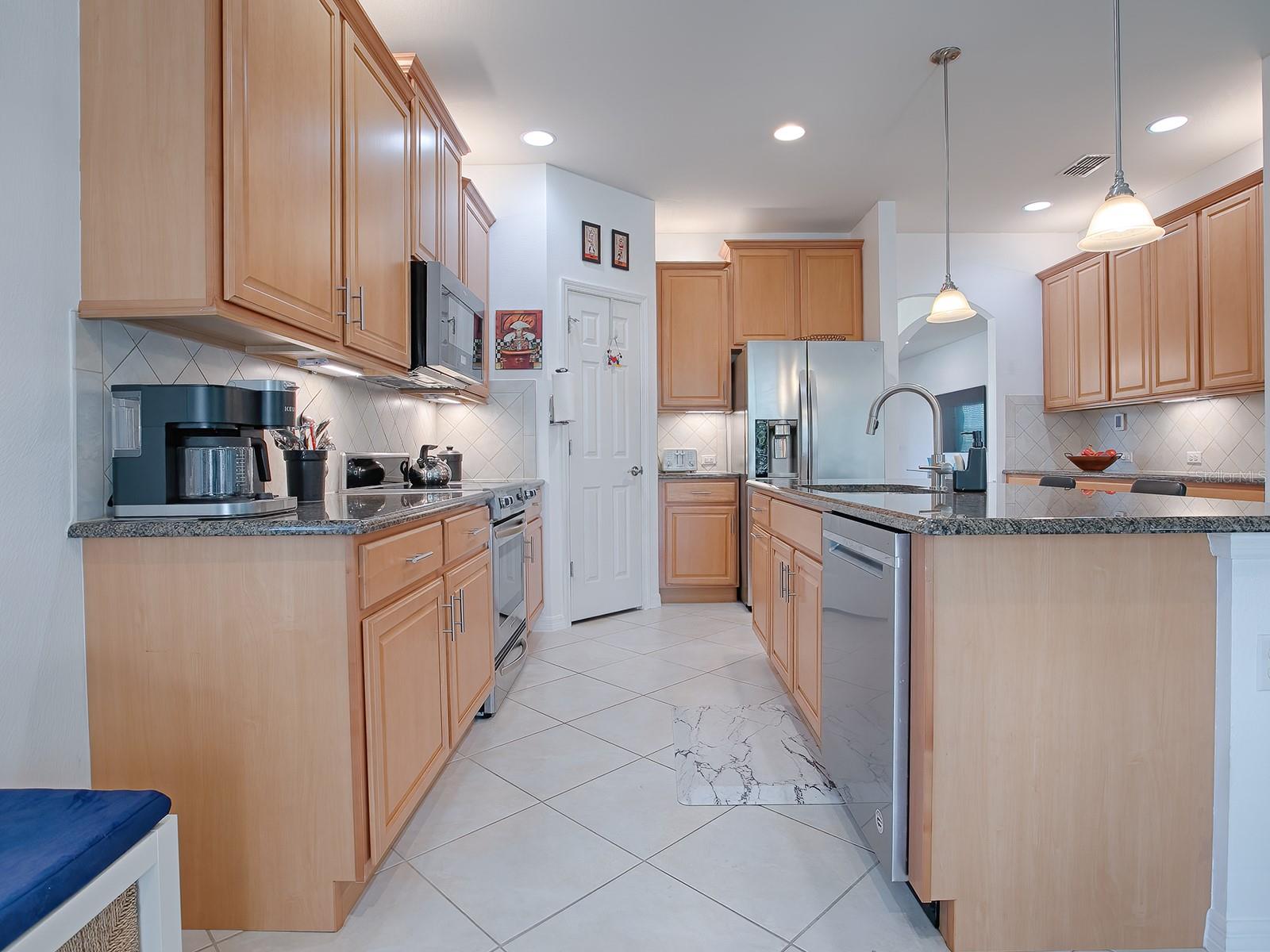 Nicely appointed kitchen with solid surface countertop, stainless appliances, loads of cabinets and accent lighting.
