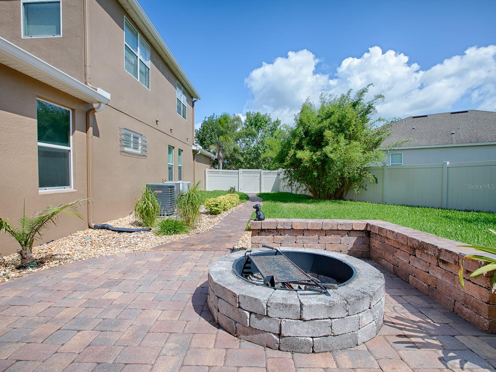Side yard with wood burning fire pit, brick wall for sitting and the paver sidewalk leading to the front yard.  So well thought out!