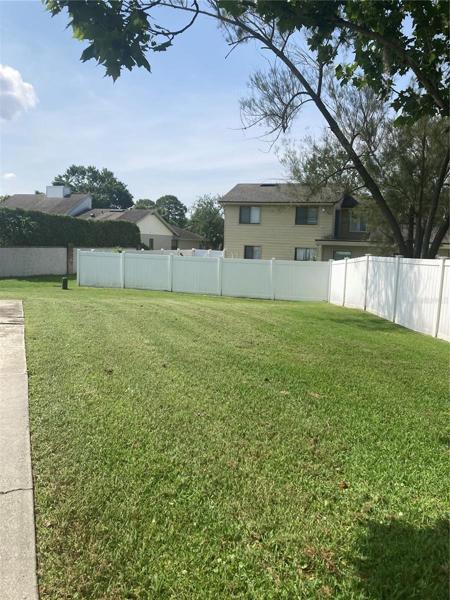 Huge grass on side yard with vinyl fence. Long driveway to the left.