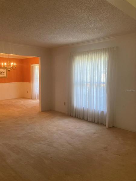 View of formal living room leading to formal dining room with bay window.