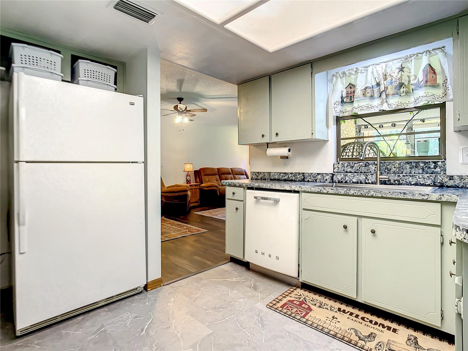 Kitchen window looks out into enclosed porch and back yard