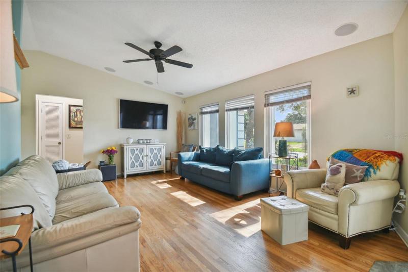 Living room with plenty of natural light and vaulted ceiling, wood flooring.