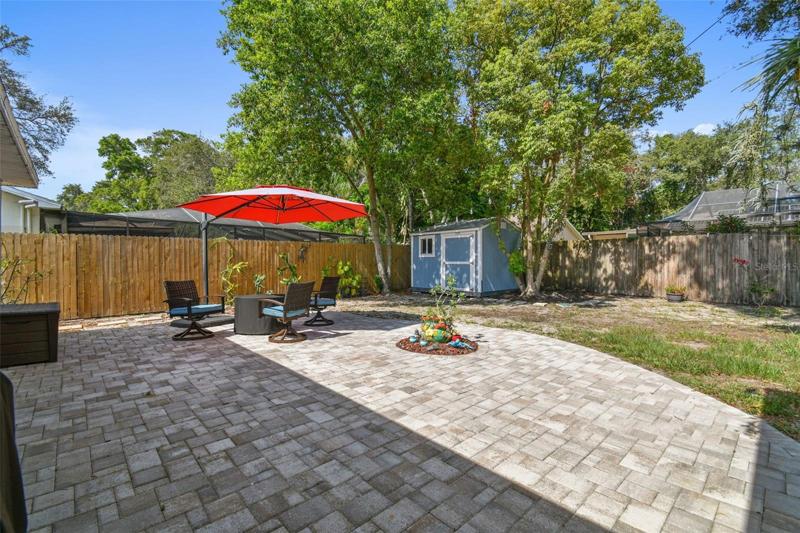 Extended pavered patio with a shed.