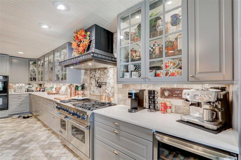 Delight in the FOUR OVENS, 48” VIKING GAS STOVE with a griddle, under cabinet lighting and ice maker, QUARTZ COUNTERS, a 13’ STAINED WALNUT ISLAND with brass kick bar under recessed lighting and even a HIDDEN PANTRY that leads to your utility/laundry room!