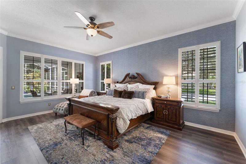 The master bedroom retreat features plantation shutters, vinyl wood look flooring and access tot he pool deck.