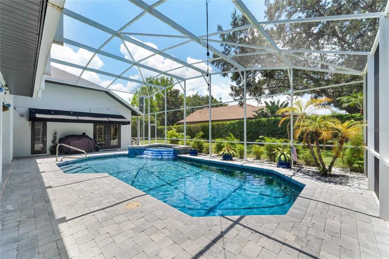 View of pool and spa with screened enclosure.