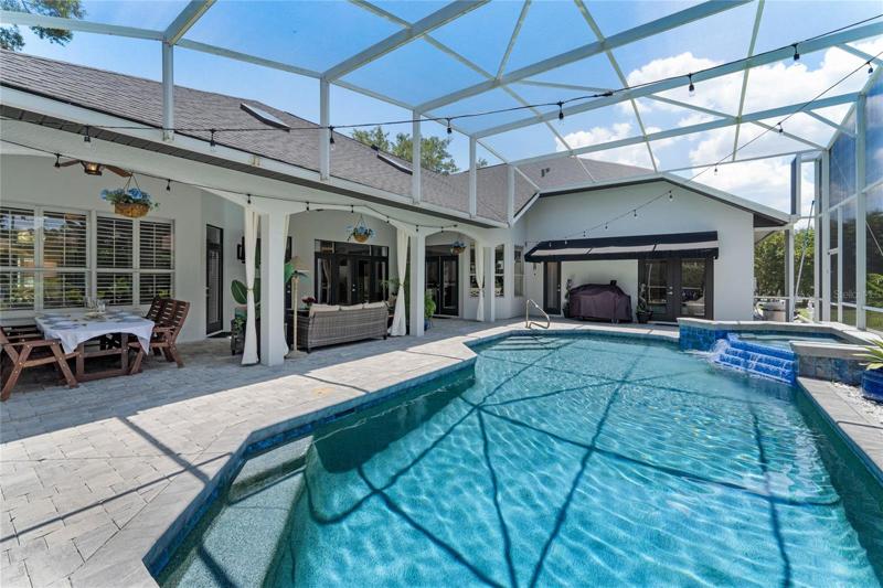 View of pool and spa with screened enclosure.
