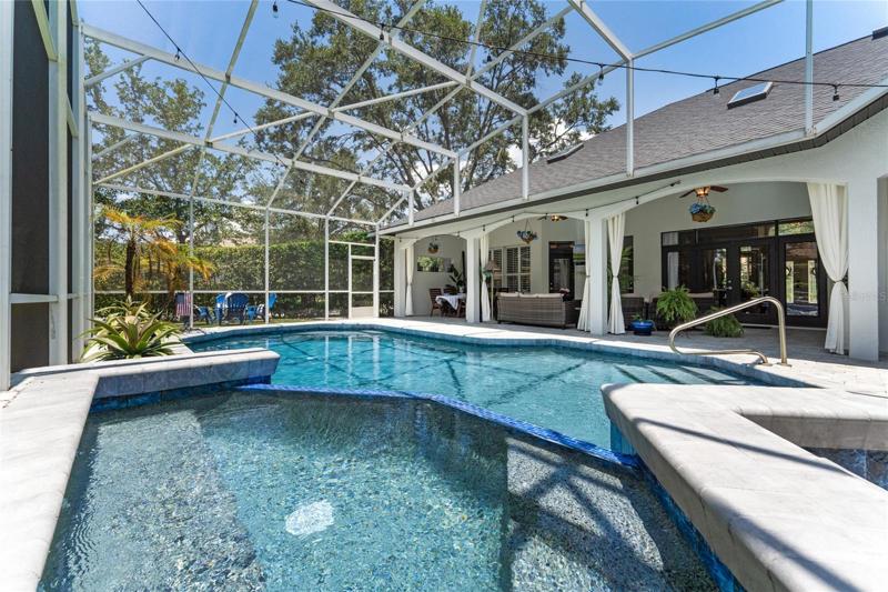 View of pool and spa with screened enclosure.