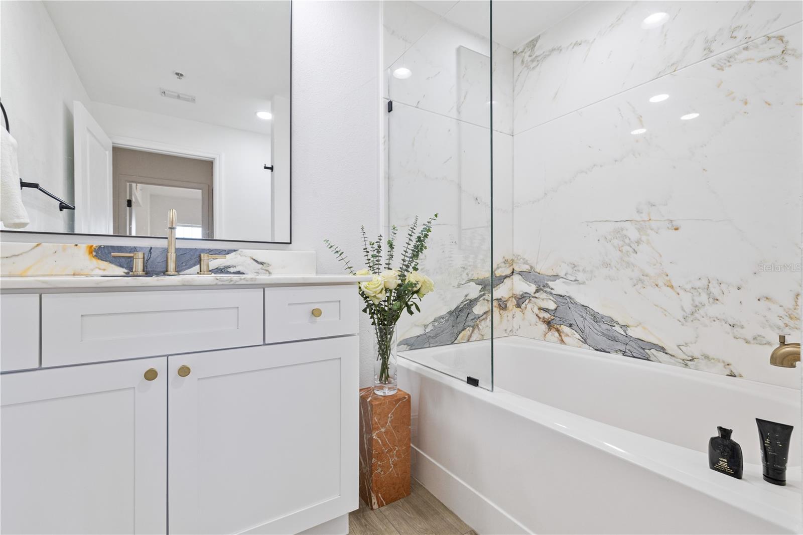 Large format marble tiles and frameless glass shower make this generous bathroom feel even larger
