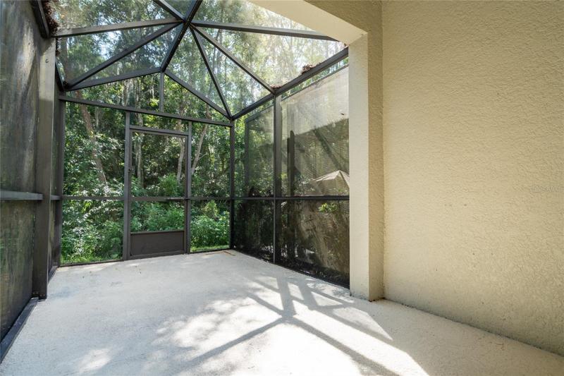 Covered lanai with screened area looks to rear forested area.