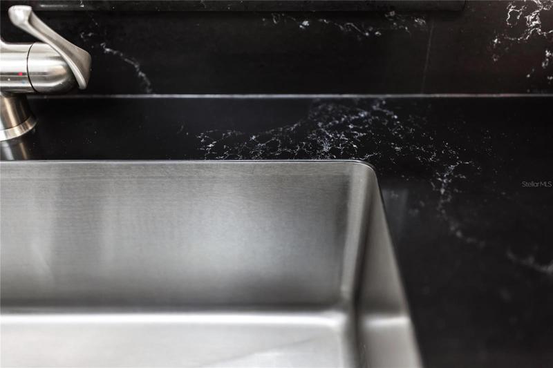 Kitchen sink installed with precision between the stone.