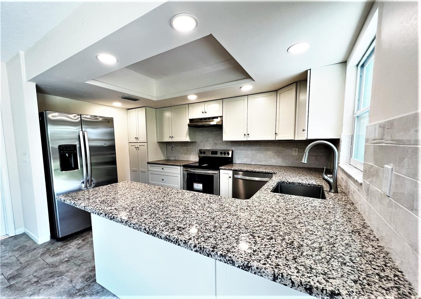 Kitchen has stainless appliances and a spacious granite breakfast bar.