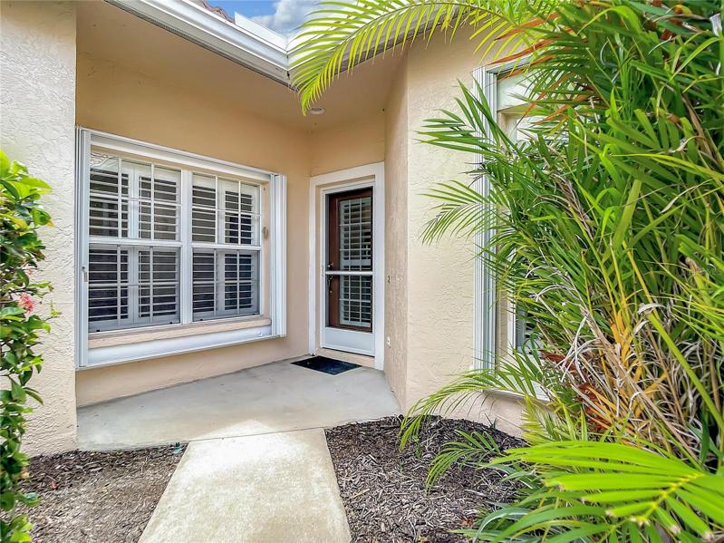 Inviting Front Entry has a covered Entrance to the Home. Please note the screen door and folding Hurrican Shutters on the door and window.