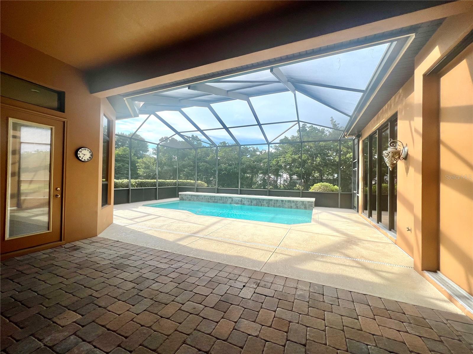 Covered patio w/ pavers opens to screened pool