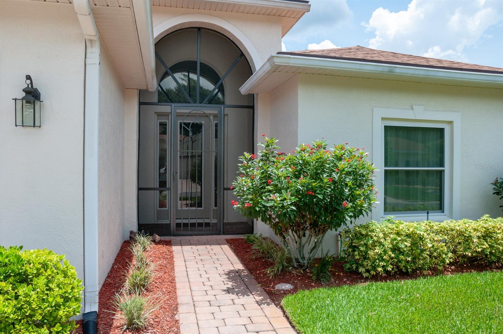 The covered and screened vaulted entry provides a warm welcome. The window is in the guest suite.