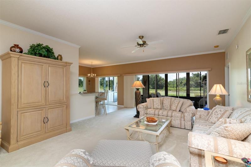 The living room has quality carpeting and ceiling fan. The triple slider opens to the enclosed covered and screened lanai.