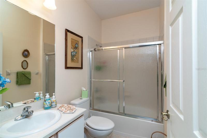 The guest bath has a combination tub and shower with a glass shower door.