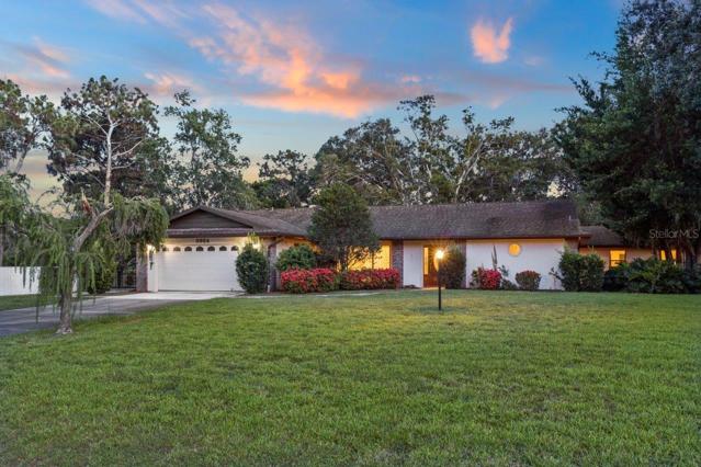 Front Elevation of the home showing the large front yard, extensive landscaping, and exterior lighting