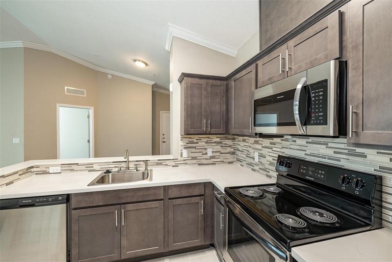 Large Open Kitchen with Quartz Counters and Beautiful backsplash!  Cabinetry has Crown Molding as well!