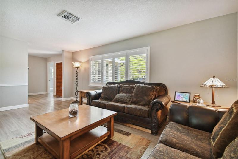Walk through the front door and the living room sets the tone with lots of natural light, plantation shutters, updated windows, fresh paint and continuous, low maintenance vinyl plank flooring.
