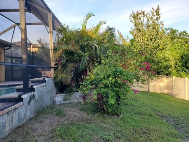 open backyard beyond screen enclosure. The backyard is complete enclosed with vinyl fencing, great for the doggie family members.