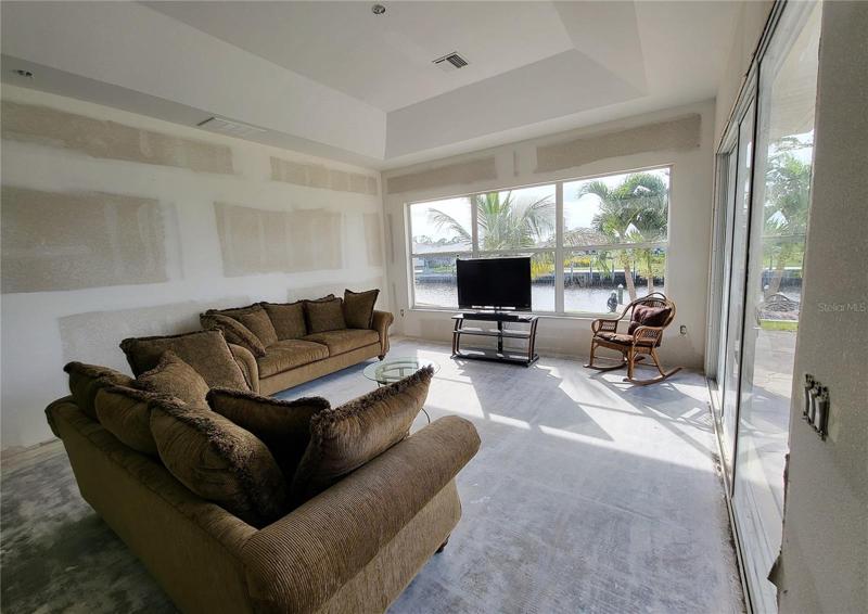 Tray ceiling, a wall of large windows facing the canal, and a triple sliding door flood this room with light