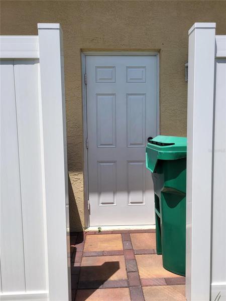 Side entrance to garage, with pavers and vinyl fence to conceal trash cans
