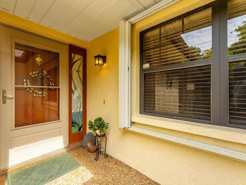 Front door entry with glass and solid door with decorative glass side light - note hurricane shutters too.