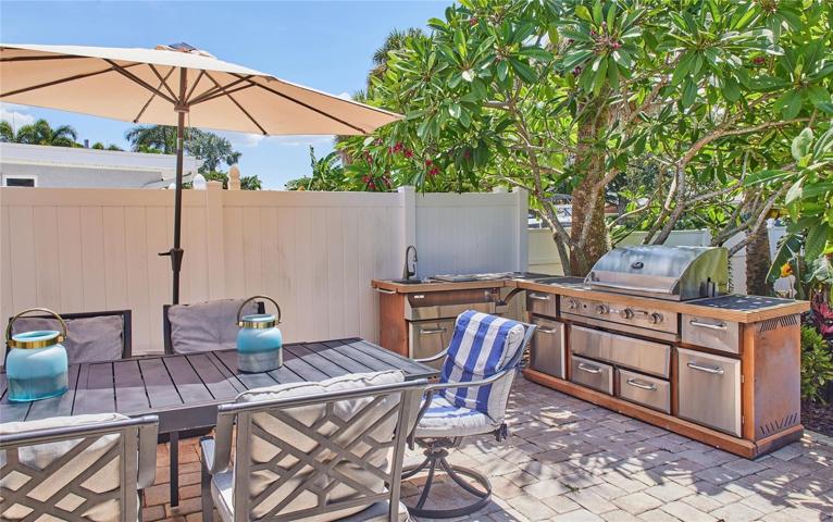 Outdoor kitchen with paved deck that follows the entire right side of the home. The kitchen has sink with running water.