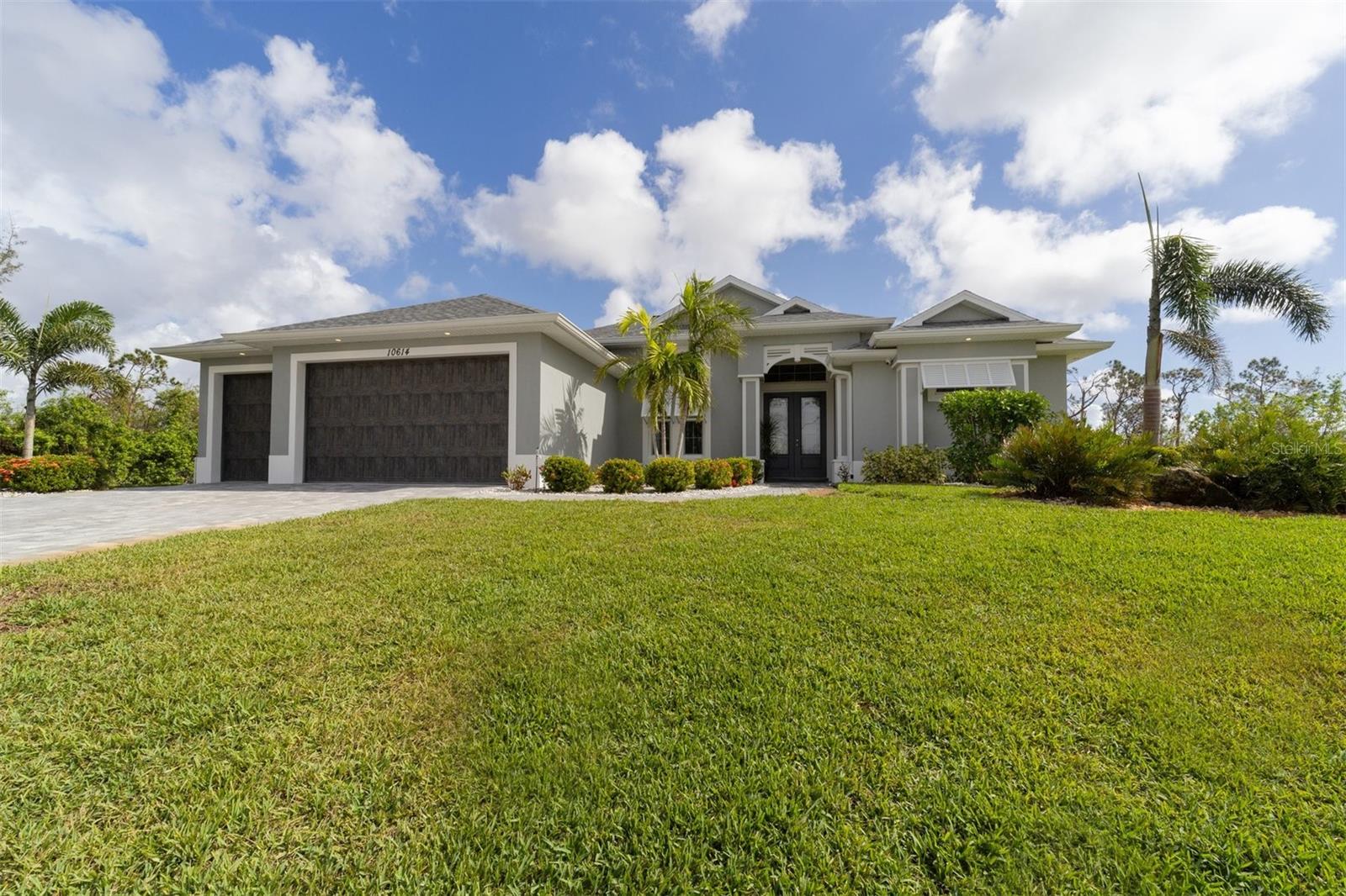 Beautiful entry past tropical plantings to double glass doors.