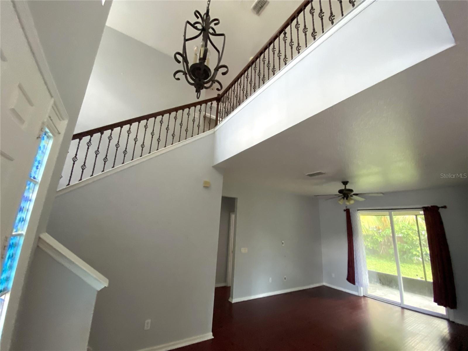 Another view of living room from dining room with front door and stairs entrance on left and a peek into the hall that leads to master bedroom in the middle