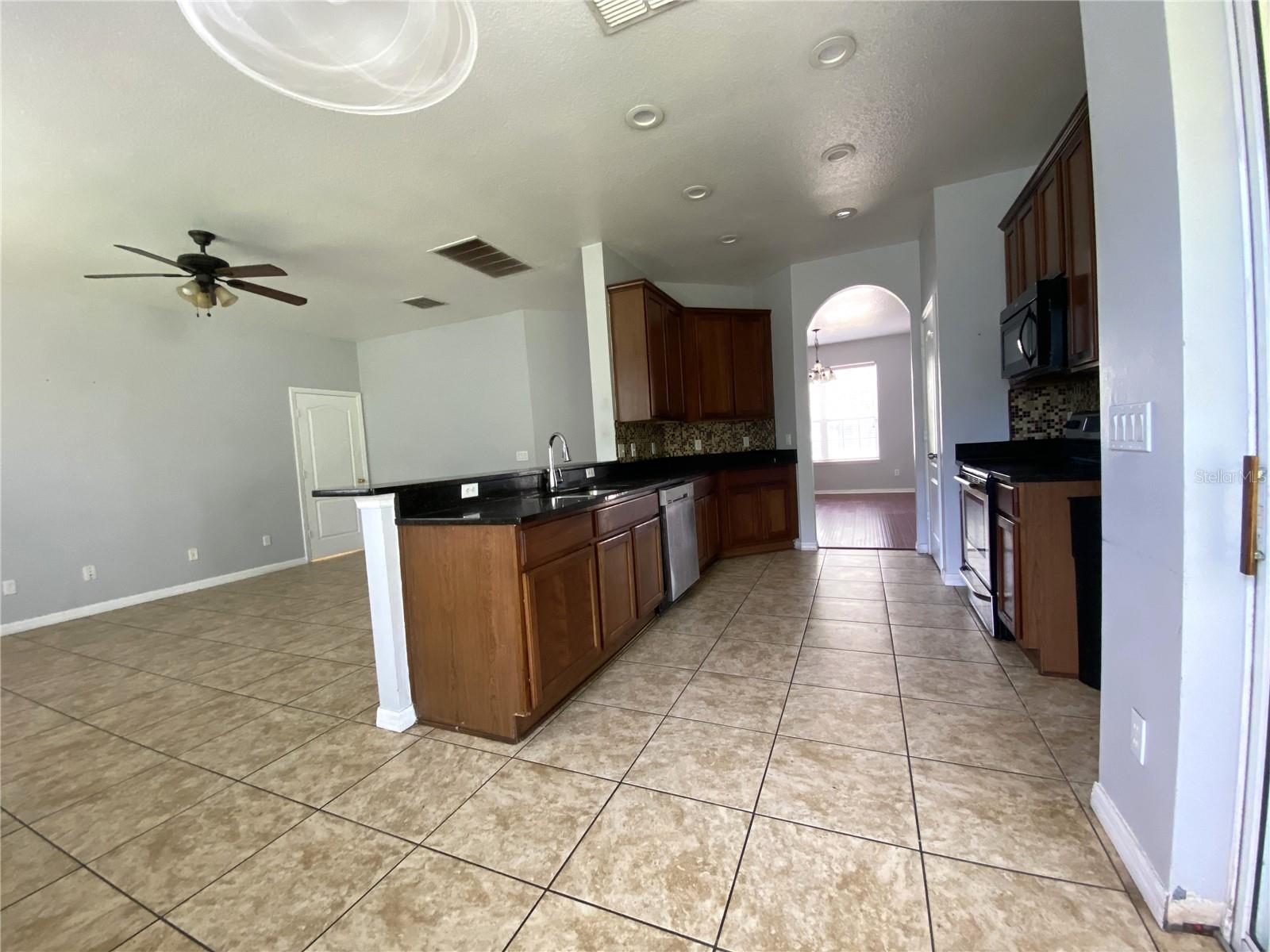 View from dinette area by slider into kitchen, bar and family room.  Door leads to laundry room and garage.