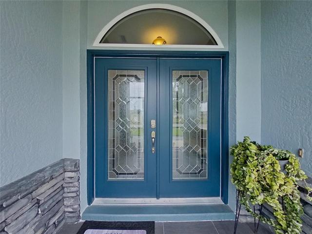 Inviting Double Door Entry. Doors are Hurricane Impact Doors and Installed 2022. Please notice the entry tile floor when you enter the Front Porch and the Stone Walls on both sides.