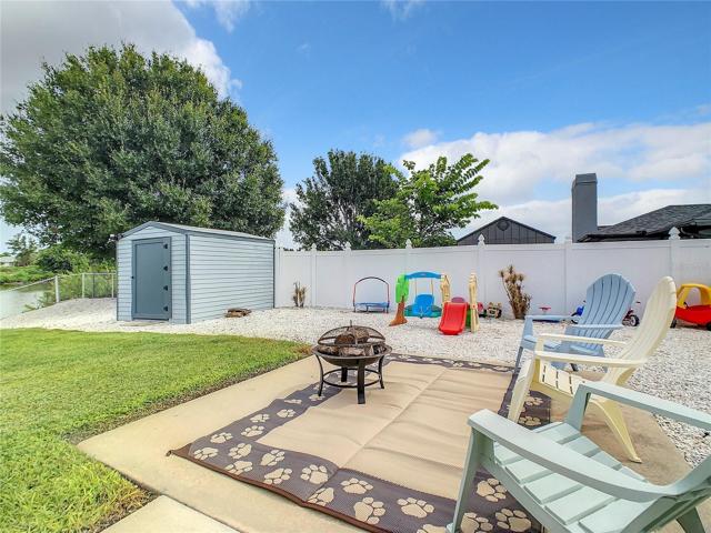 Fire Pit for Roasting Marshmallows and cooking Hotdogs and provides a nice Romantic Atmosphere. Large wood storage shed is painted to match the home. White Vinyl Privacy fence on the right.