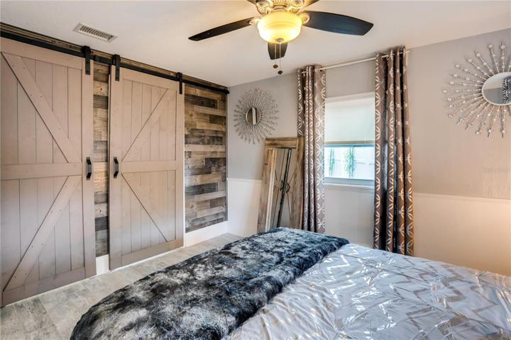 Custom reclaimed wood wall in the Master Bedroom beautifully frames the custom barn doors