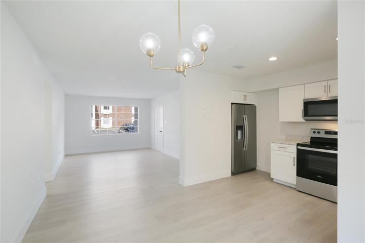 Step inside to luxury vinyl tile flooring leading to a kitchen with stainless steel appliances and sleek quartz countertops.