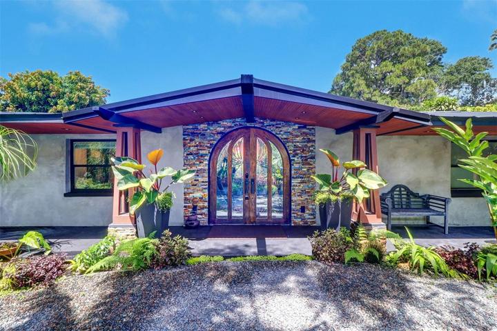 This mid century modern home was architecturally resurrected from a Frank Lloyd Wright original bungalow design. The beautifully designed entry way showing the tongue and grove cedar soffit and the solid oak pergola beams accenting the approximately 100 year old rounded refinished oak door with stunning Magnolia Blossom leaded glass panels.  The porch extends the length of the front accented by 4 illuminated skeleton bungalow pillars with a 6 ft overhang.