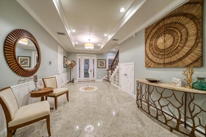 Gorgeously appointed foyer, with beautiful granite tile work, under-stairs built-in shelving and storage, and attractive lighting.