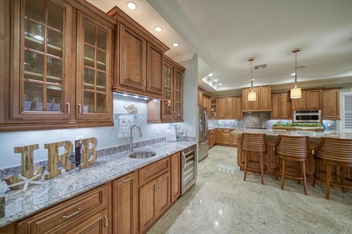Wet bar with beverage refrigerator, pull out storage, customized cabinetry, and attractive glass door fronts.
