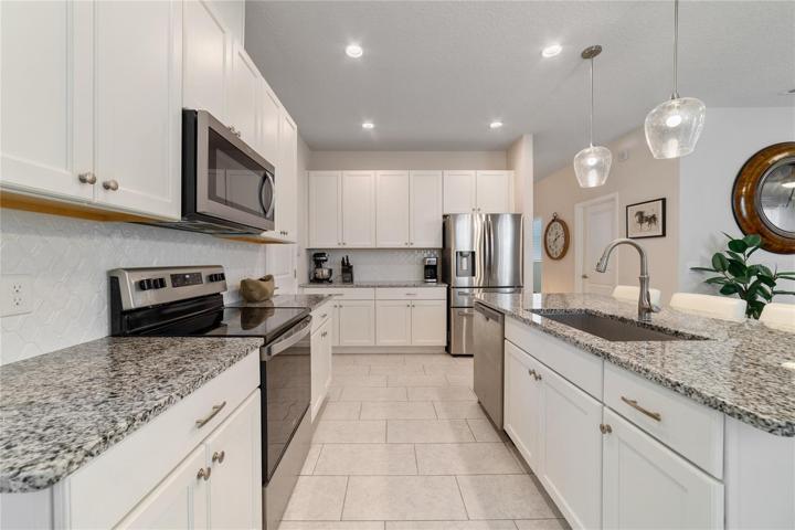 The family chef will appreciate being surrounded by beautiful shaker style cabinetry with soft close doors, CUSTOM TILED BACKSPLASH, stainless steel appliances and a large island under pendant lighting with breakfast bar seating for casual dining or entertaining!